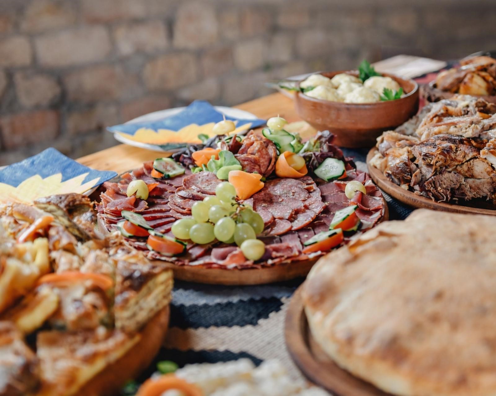 Tradicionalna trpeza sa domaćim mesom, suhomesnatim proizvodima, hlebom i salatama u Etno selu Vidikovac